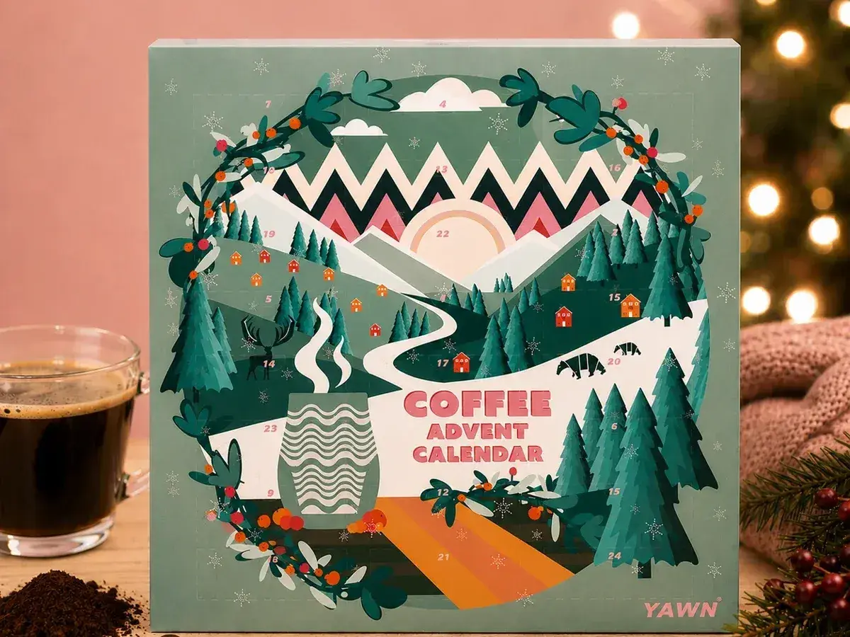 Illustrated YAWN coffee advent calendar next to a glass of coffee
