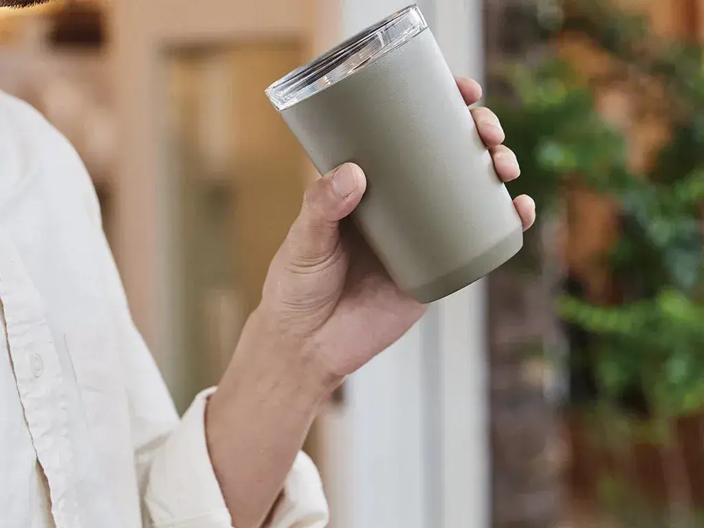 Hand holding a KINTO To Go Tumbler outdoors
