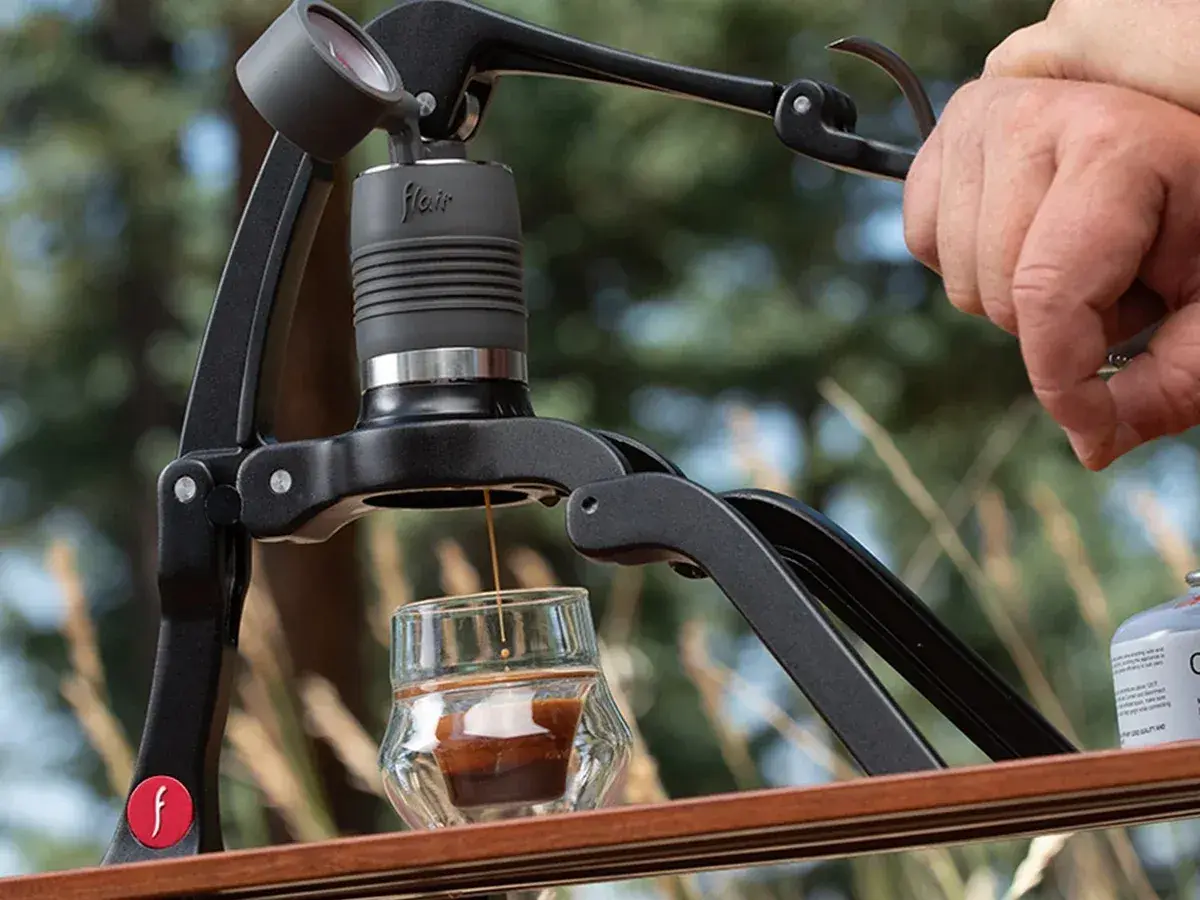 Hand pressing the lever of a Flair 2GO espresso maker outdoors