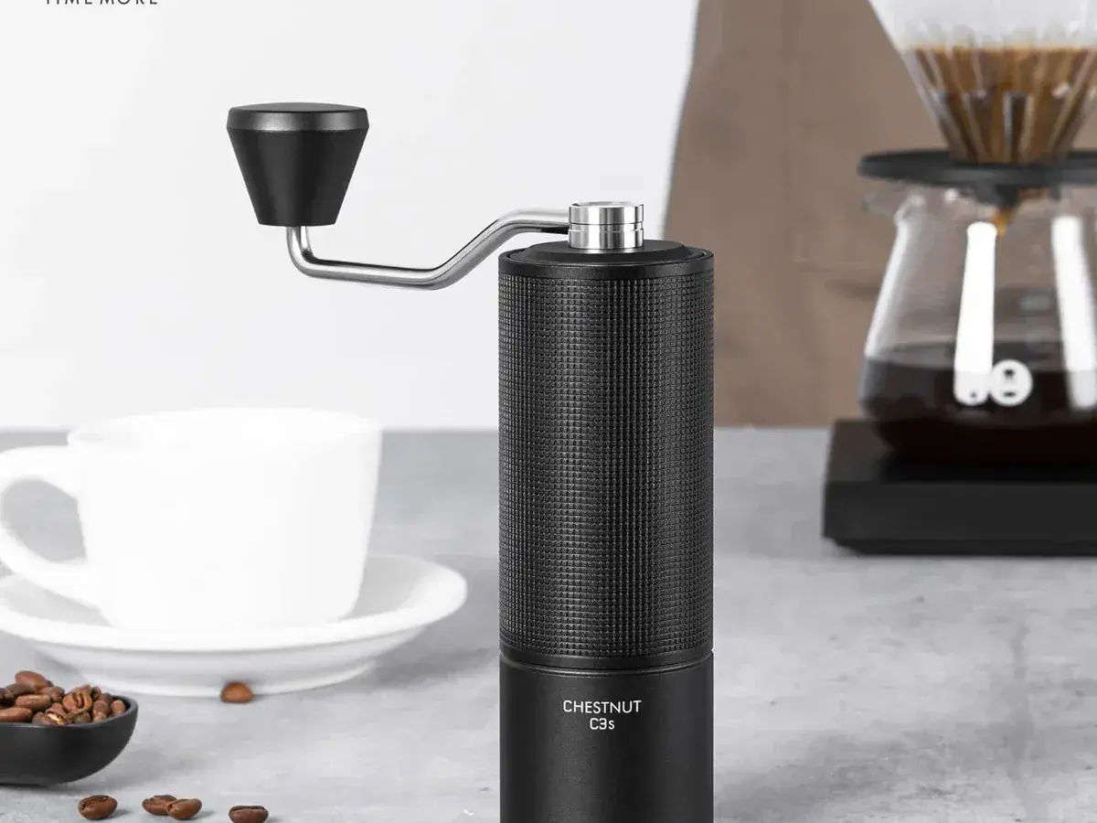 Black Timemore Chestnut C3S hand grinder on a kitchen counter next to a pour-over setup