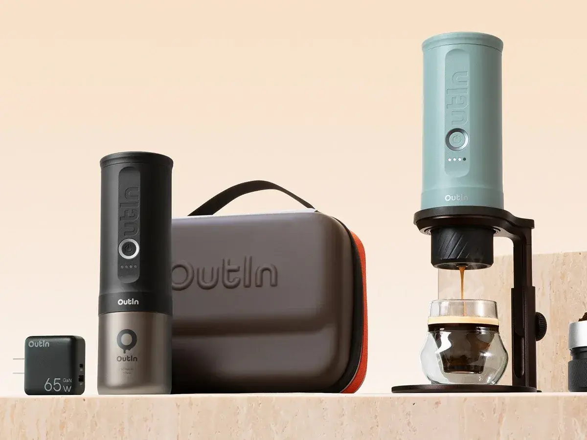 Two OutIn Nano 2 espresso makers, one brewing into a glass, next to their carry case